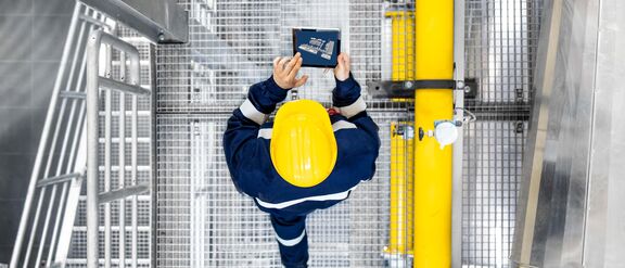 Picture showing a worker walking with a tablet, seen from above